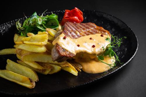 a black plate with a piece of meat and french fries at Pensiunea Casa Weiss in Rimetea