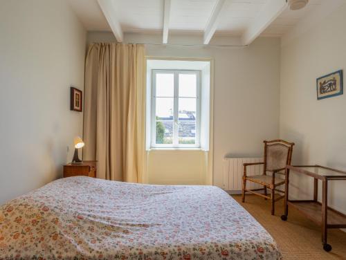 une chambre avec un lit, une fenêtre et une chaise dans l'établissement Maison au cœur de Locquirec, à Locquirec