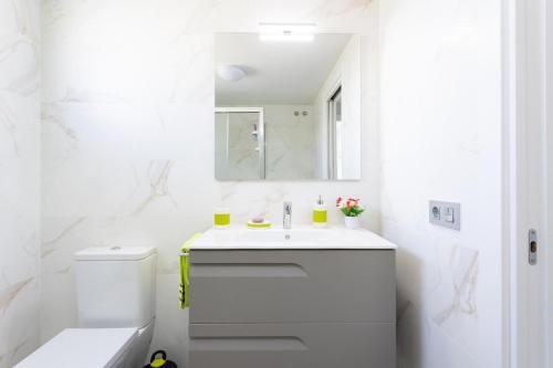 a white bathroom with a sink and a toilet at La Tejita, comfortable one-bedroom apartment in El Médano