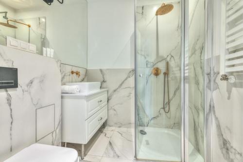 a white bathroom with a shower and a toilet at Old Town Długa by NorthSide Apartments in Gdańsk
