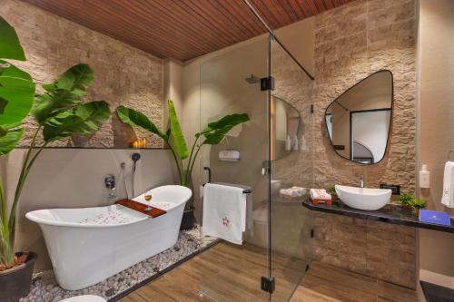 a bathroom with a tub and two sinks and a mirror at SaffronStays Episode in Jāmb