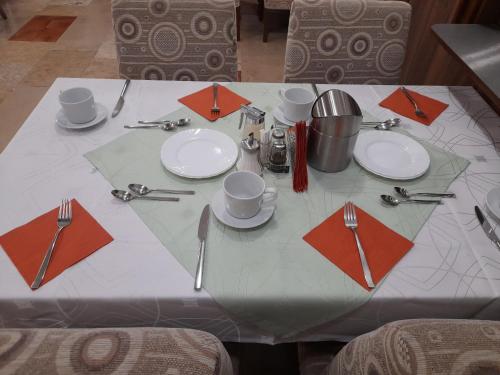 a white table with plates and utensils on it at Mátraházai Üdülőház in Mátraháza