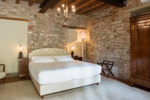 a bedroom with a white bed and a stone wall at Classique in Lazise