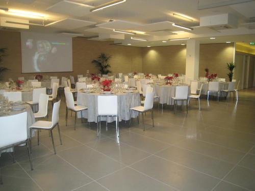 a banquet hall with white tables and white chairs at Blu Arena Hotel in Montecchio