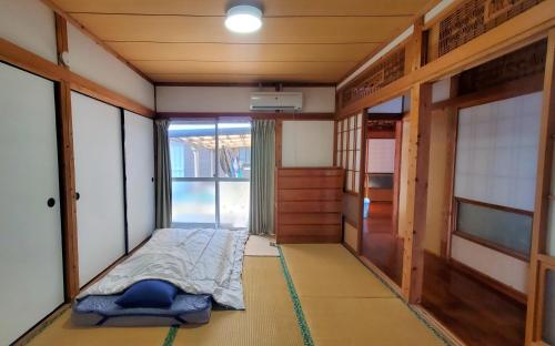 a small room with a bed and a window at 一棟貸し 喜瀬しーばなゲストハウス -Traditional House Rent- in Amami