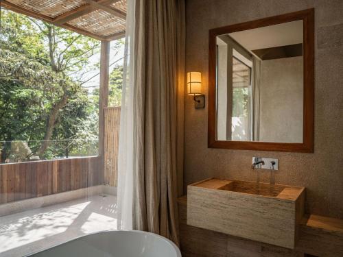 une salle de bain avec un lavabo, un miroir et une baignoire dans l'établissement Sanyea You Gan Wan Secluded Resort Hotel-Free Yacht Experience, à Shenzhen