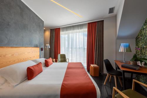 a hotel room with a large bed and a desk at Wellness Spa Hotel Principe Fitalia in Siracusa