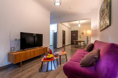 een woonkamer met een paarse bank en een tv bij Industrial-Style Apt in Psyrri, Walk to Acropolis in Athene