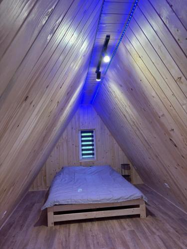 a bed in a wooden room with a roof at Domek w lesie in Gnojno