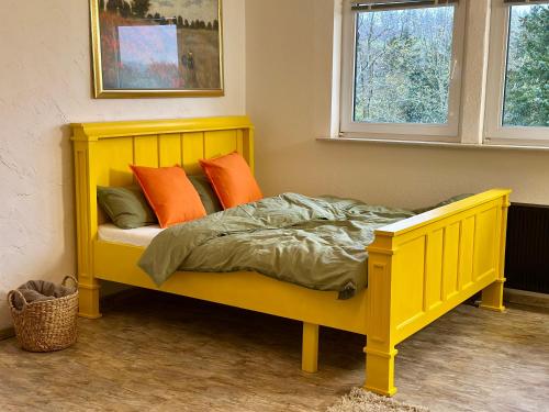 a yellow bed with orange pillows in a room at Charmante Wohnung in Top Lage in Medebach