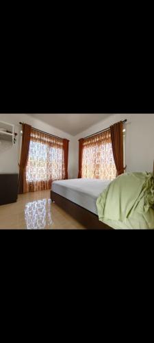 - une chambre avec un lit et 2 fenêtres avec des rideaux dans l'établissement Villa Istana Fitri, à Situ 2