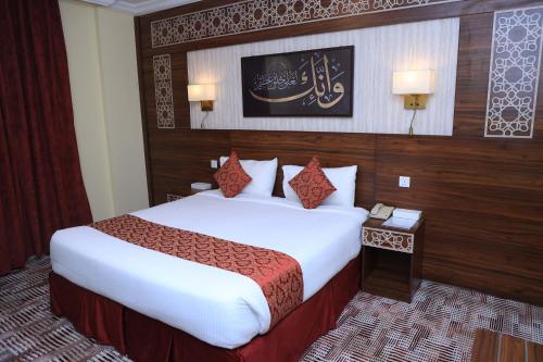 a hotel room with a bed and a table with a phone at Abraj Al Tayseer Tuwa Hotel in Makkah
