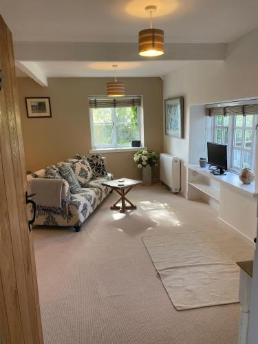 a living room with a couch and a table at Gardeners Cottage in Mudford