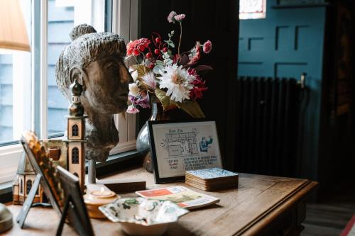 a table with a vase of flowers and a statue at Sheddington Manor - 2 Bedroom Guest House & Cinema in Belfast
