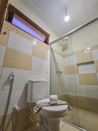 a bathroom with a toilet and a glass shower at Canto Verde Pousada in Lençóis