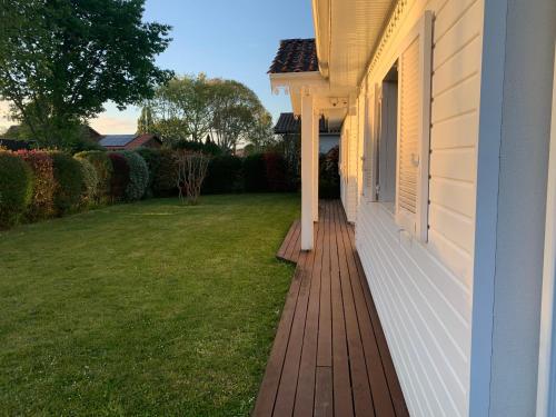 une terrasse couverte d'une maison avec une pelouse dans l'établissement Villa du paradis des canards, à La Teste-de-Buch