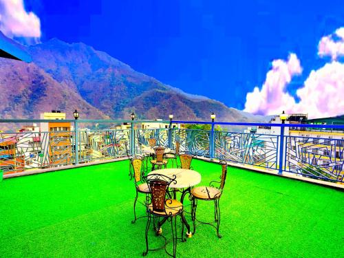a table and chairs on a balcony with a mountain at LA Riqueza Pride Inn # Rootop Swimming Pool with Mountain View # Free Parking # Tapovan # Center of Rishikesh# in Rishīkesh