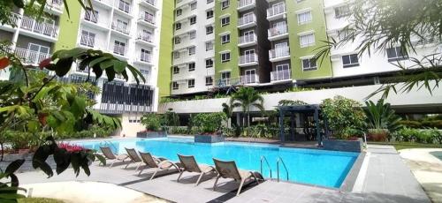 ein Pool mit Stühlen vor einigen Gebäuden in der Unterkunft Mesatierra Garden Residence 2005 in Davao City