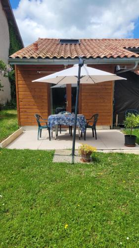 a table and chairs under an umbrella in a yard at Reflet de Bien Être in Marsoulas