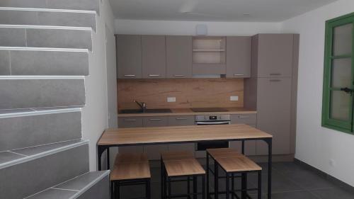 - une cuisine avec une table et des tabourets en bois dans l'établissement Maison cosy, à Saint-Gilles