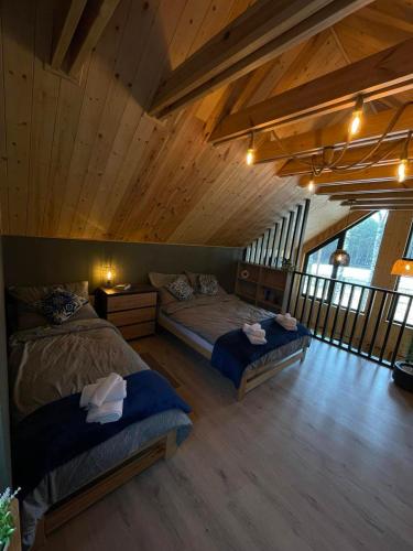 a bedroom with two beds in a room with wooden ceilings at Leśne Domki in Życiny