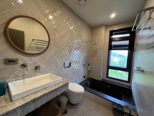 a bathroom with a sink and a toilet and a mirror at Piano Hotel in Xiaoliuqiu