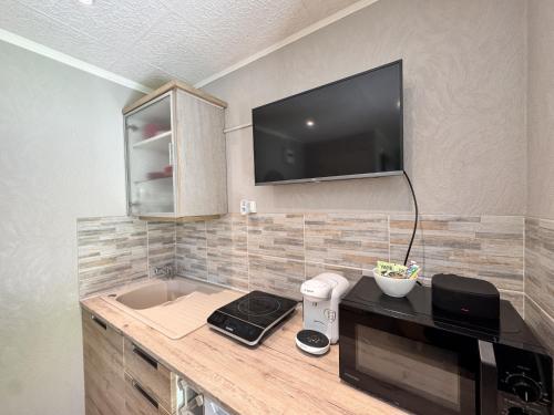 une cuisine avec un comptoir avec une télévision au mur dans l'établissement L'Abbaye de l'Epau - Jardin - Rivière, au Mans