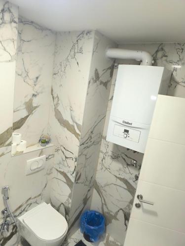 a bathroom with a toilet and a marble wall at Luxury apartments Sarajevo-free parking in Sarajevo