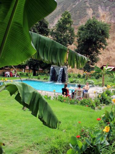 a group of people sitting around a pool with a waterfall at Oasis Paraiso Ecolodge in Cabanaconde
