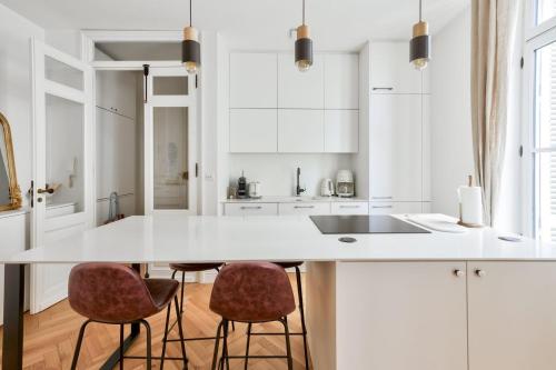 une cuisine avec un comptoir blanc et deux tabourets dans l'établissement GuestReady - Sunny Retreat with Tower Views, à Bordeaux