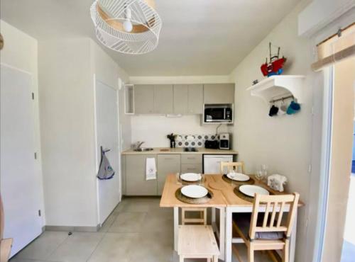 une cuisine avec une table et des chaises dans une cuisine dans l'établissement Appartement Remember à 700m de l'Océan, à Mimizan-Plage