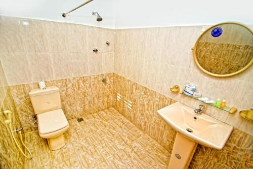 a bathroom with a toilet and a sink and a mirror at Thilaka City Hotel in Anuradhapura