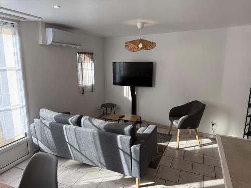 a living room with a couch and a flat screen tv at Résidence des Lilas - Orgelet - Lac de Vouglans in Orgelet