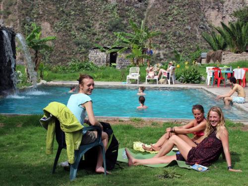 a group of people sitting in the grass by a pool at Oasis Paraiso Ecolodge in Cabanaconde