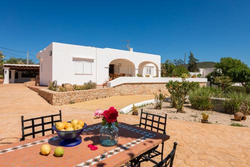 a table with a bowl of fruit and a vase of flowers at Villa Can Blai in Santa Eularia des Riu