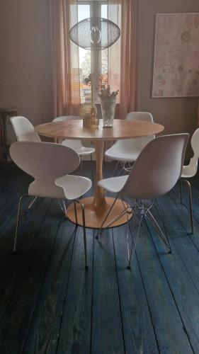 a dining room table with white chairs and a table and aandelier at Beautiful and romantic 2 bedroom villa on the island Aeroe in Søby