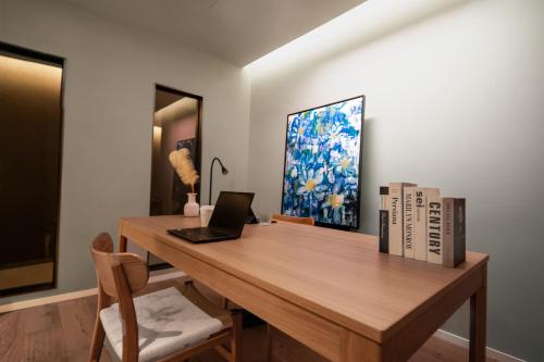 a wooden desk with a laptop and books on it at The Yard Boutique Hotel Shanghai 一隅酒店上海虹桥漕河泾店 in Shanghai