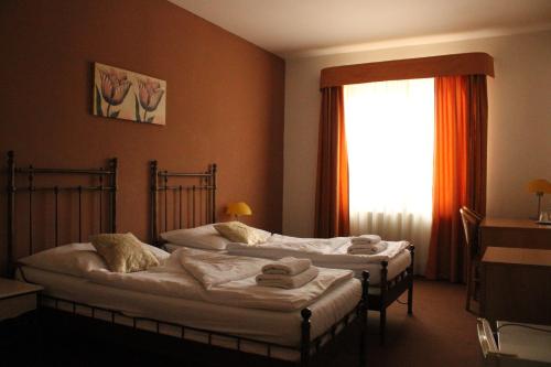 two beds in a hotel room with a window at Sporthotel Patriot in Litoměřice