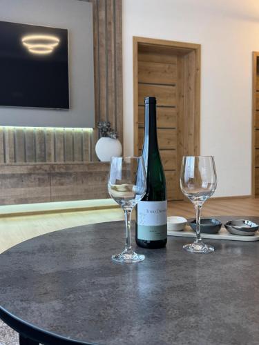 a bottle of wine and two wine glasses on a table at Apartmán Brezovina Lux in Veselé
