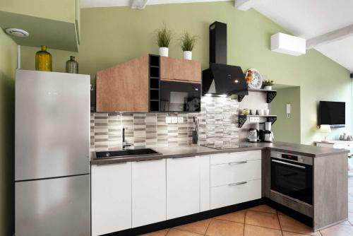 une cuisine avec des armoires blanches et un réfrigérateur en acier inoxydable dans l'établissement Le Tranquille characterful apartment, à Carcassonne