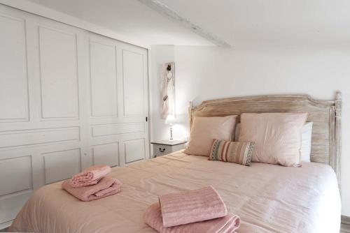 une chambre avec un lit avec des serviettes roses dessus dans l'établissement Le Tranquille characterful apartment, à Carcassonne