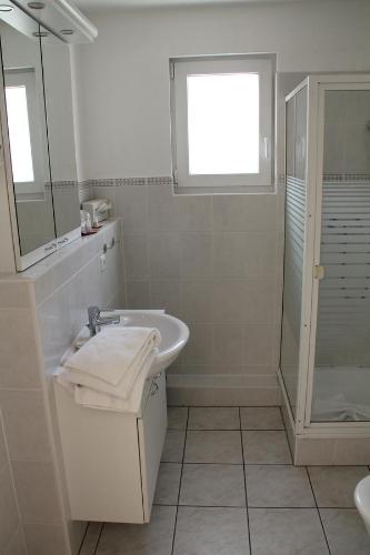 a white bathroom with a sink and a shower at Apartment am Großen Plöner See in Ascheberg
