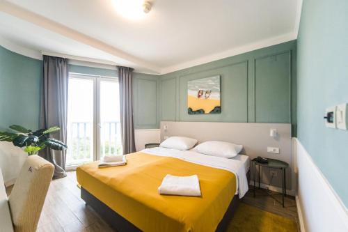 a bedroom with a large bed with a yellow blanket at Hotel Plaza in Pag