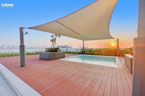 a patio with a swimming pool under a white umbrella at bnbmehomes - Anwa in Dubai