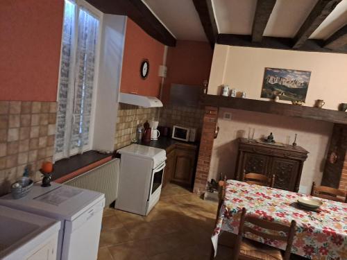 a kitchen with a table and a stove and a refrigerator at Maison avec vue sur la campagne in Viersat