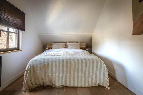 a small bedroom with a bed with a striped bedspread at Vakantiehuis Zand7 in Lommel