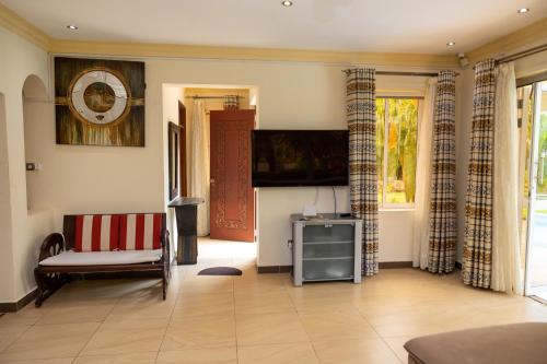 a living room with a couch and a flat screen tv at Tamasha Luxury Villa - Diani in Diani Beach