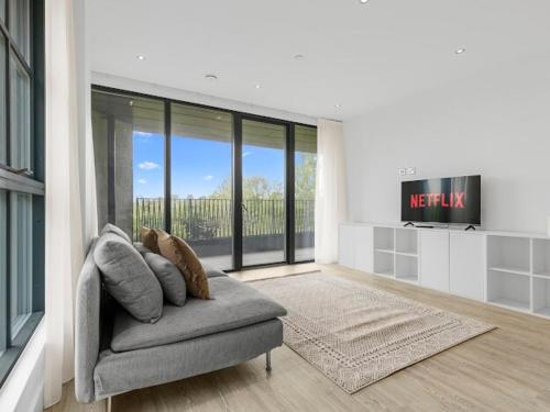 a living room with a couch and a large window at Modern Flat in Central Cambridge in Girton