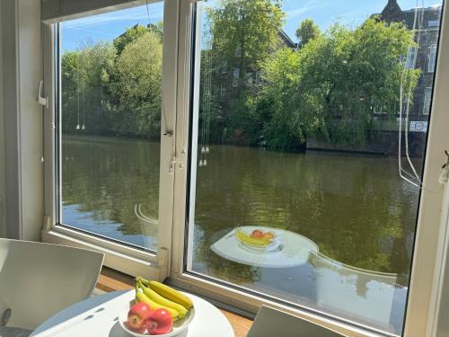 a plate of fruit on a table in front of a window at Peaceful room on a houseboat in the city centre in Amsterdam