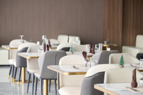 Un comedor con mesas y sillas blancas. en Apartment 306 At Oasis Park, en Kigali